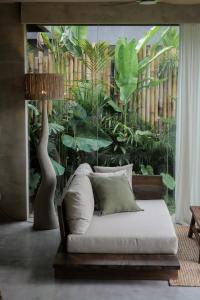 a bedroom with a bed and a large window with plants at Utopia Concept Bali - Adults Only in Ubud