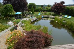 a pond in a garden with chairs and an umbrella at Klein und Fein in Hartberg