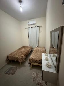 a small room with two beds and a mirror at Golden Dunes in Tozeur