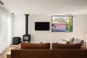a living room with a brown couch and a flat screen tv at Apartment Two - Apartments on Gavan in Bright
