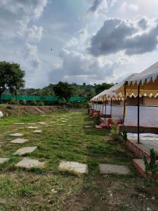 a row of tents in a field with grass at Aura Resort and Restaurant in Chikalthān