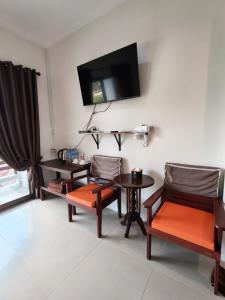 a living room with two chairs and a table and a tv at Jigsaw Cafe & Resort in Ban Na We