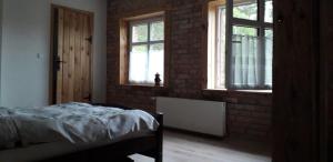 a bedroom with a brick wall and a bed and windows at Izdebka in Bochowo
