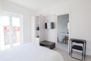 a white bedroom with a bed and a desk at ARQO Apartments in Marcianise