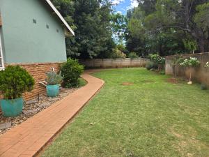 a yard with a brick walkway next to a house at Modern rustic private flat in Bloemfontein +2 photos