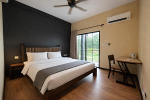 a bedroom with a bed and a desk and a window at Papalu Villa in Kuala Penyu