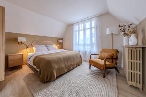 a bedroom with a large bed and a chair at La Villa des Coccinelles in Olivet