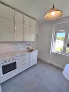 a kitchen with white cabinets and a window at Villa Hortensia in Aszófő