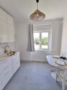 a white kitchen with a table and a window at Villa Hortensia in Aszófő +6 photos