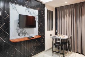 a room with a table and a tv on a wall at Hotel Samarth Elite Baner - Indian Guests Only in Pune +20 photos