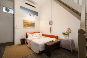 a bedroom with a bed and a table at Non Inn The Post and Barber 3 Bedroom Riverside Shophouse with King and Twin Rooms in Bang Rak