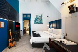 a bedroom with a bed and a desk and a guitar at Non Inn The Post and Barber 3 Bedroom Riverside Shophouse with King and Twin Rooms in Bang Rak