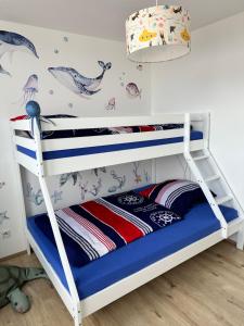 a white bunk bed in a childs room with narwhal wallpaper at Ebbe u Flut Bremerhaven in Bremerhaven