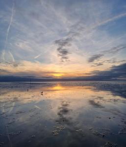 a sunset on a beach with the reflection in the water at Ebbe u Flut Bremerhaven in Bremerhaven +2 photos