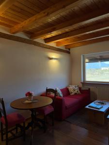a living room with a red couch and a table at AGRITURISMO MODOLO Belluno Dolomiti in Belluno