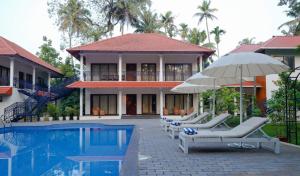 a villa with a pool and chairs and an umbrella at River Whisper Villa in Cochin