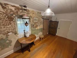 a room with a wooden table in a room with a wall at Bathurst River House B & B in Bathurst
