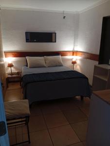 ein Schlafzimmer mit einem Bett, zwei Lampen und einem Fernseher in der Unterkunft Hostel 566 in La Serena