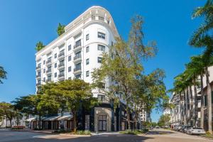 a white building on a street with trees at The Avenue Coral Gables in Miami