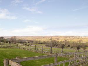 a wooden fence in a field with hills in the background at Brandy's Barn in Middleham