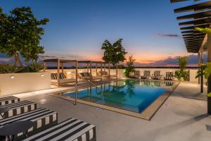 a swimming pool with chairs and a sunset in the background at The Avenue Coral Gables in Miami