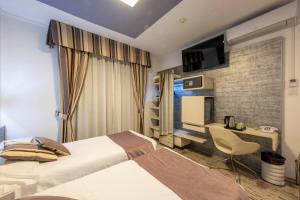 a hotel room with two beds and a desk at Hotel Le Palme Lago Maggiore Bike Friendly in Dormelletto