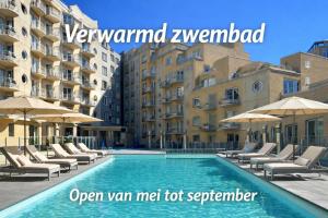 a swimming pool with chairs and umbrellas in front of buildings at Studio zwembad met frontaal zeezicht in Ostend +18 photos