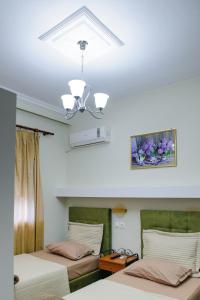 a bedroom with two beds and a ceiling with a chandelier at Hotel Makedonia in Évzonoi