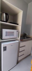 a kitchen with a microwave on top of a refrigerator at Studio Container Morano Calabro in Florianópolis