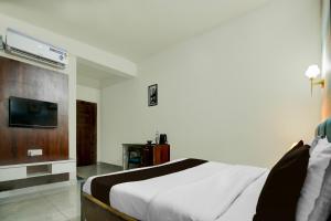 a bedroom with a bed and a flat screen tv at Hotel O Riddhinn6 in Jalandhar +30 photos
