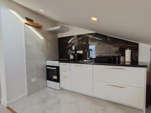 a kitchen with white cabinets and a black counter top at Guesthouse Podaca in Podaca