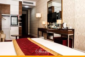 a hotel room with a bed and a desk with a television at Shams Albasra Hotel in Al Başrah