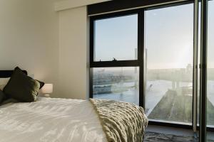 a bedroom with a bed and a large window at River View 1BR Docklands Apartment sleeps 3 in Melbourne +25 photos