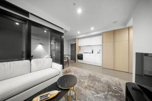 a living room with a white couch and a kitchen at River View 1BR Docklands Apartment sleeps 3 in Melbourne