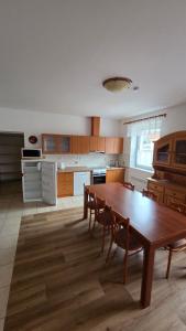 a large kitchen with a wooden table and chairs at Pension Úsvit in Podkopná Lhota