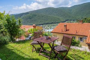 a wooden table and two chairs on a lawn with a view at Studio for short stay in Rabac