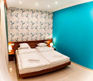 a bedroom with two beds and a blue wall at Mia Casa Hotel Yerevan in Yerevan