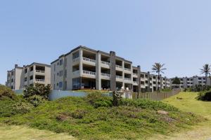 an apartment building on the beach with a hill at Laguna La Crete 119 in Uvongo Beach