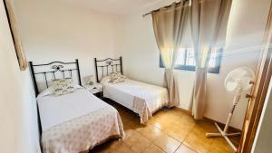 a bedroom with two beds and a fan at Apartamentos Ajabo Adeje in Adeje