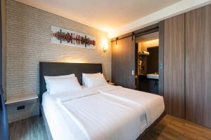 a bedroom with a large white bed with a brick wall at BB House Rangsit บีบี เฮ้าส์ รังสิต in Ban Talat Rangsit