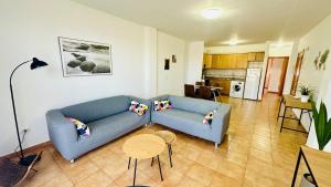a living room with a blue couch and a table at Apartamentos Ajabo Adeje in Adeje +17 photos