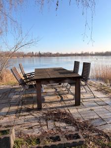 a wooden picnic table and chairs next to a lake at Gästehaus am Privatsee in Biederitz