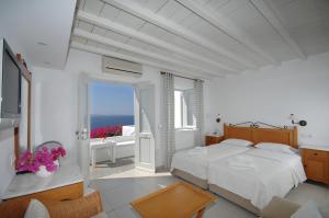 a white bedroom with a bed and a balcony at Mykonos View Hotel in Mikonos +58 photos