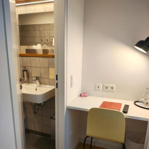 a bathroom with a sink and a desk with a chair at Hotel Brandenburger Dom in Brandenburg an der Havel +25 photos