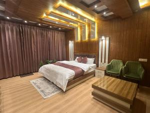 a bedroom with a bed and two green chairs at Willow Winds Home Stay in Theog