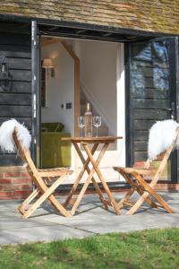 a wooden table and two chairs with white faux fur at Little Larks Barn in Felsted Station