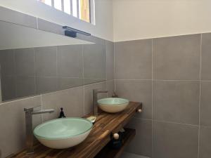 two sinks on a wooden counter in a bathroom at Villa exceptionnelle en bord de mer - SUNSET VILLA in Pointe-Noire
