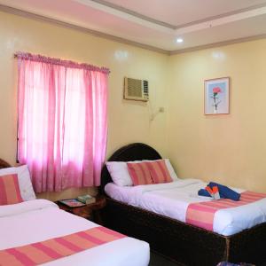 two beds in a room with pink curtains at RR Family Spring Resort in Maramag