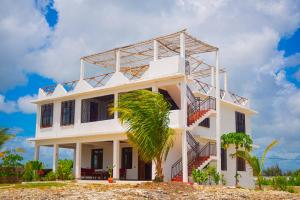 a white house with a palm tree in front of it at Villa Katerina-Zanzibar Apartment Paje in Paje