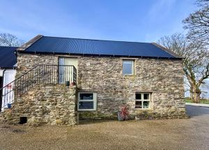 a stone house with a solar roof on a street at Foyle View Glebe Barn in Tullyverry